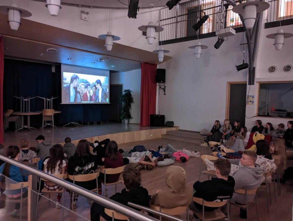 Unglingastig flatmagar í salnum og horfir á Grease